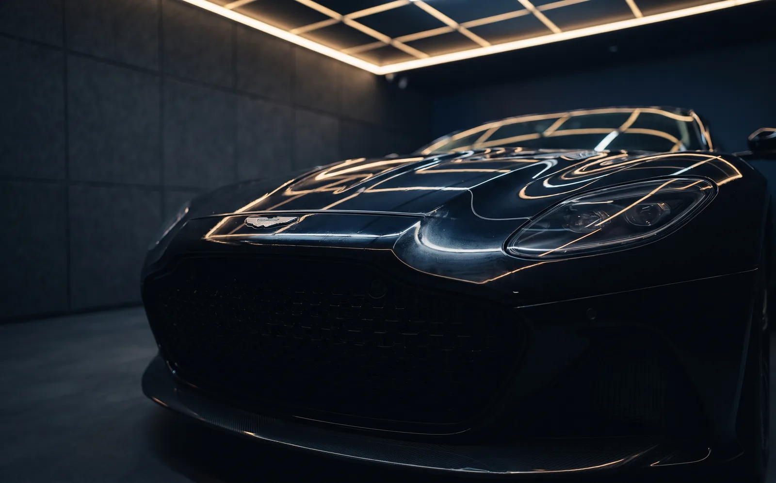 Aston Martin noire dans un studio aux lumières dorées, carrosserie lisse après la pose du PPF